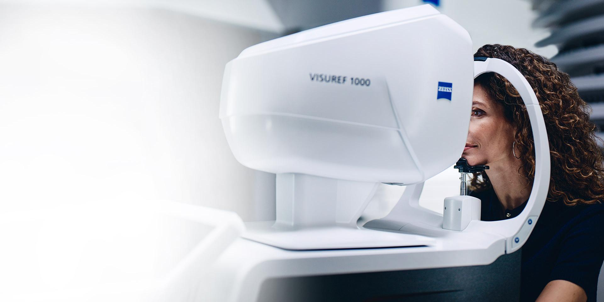En kvinna tittar genom ZEISS VISUREF 1000.