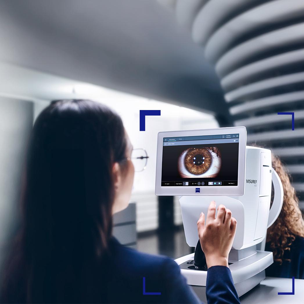 En kvinnlig optiker tittar på skärmen för ZEISS VISUREF 600, där en bild av ett öga visas.