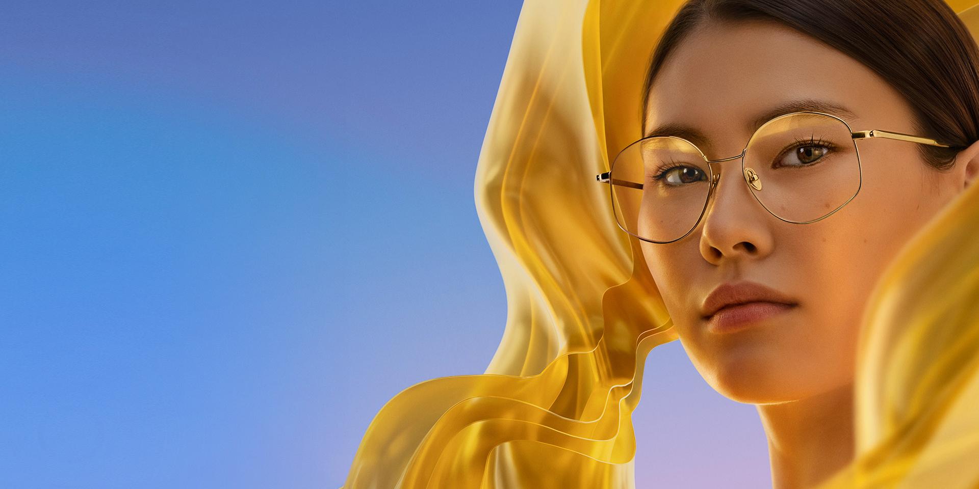 En kvinna bär klara glasögon med ZEISS DuraVision Gold UV, som ger en diskret men ändå distinkt guldfärgad reflex på glasen.