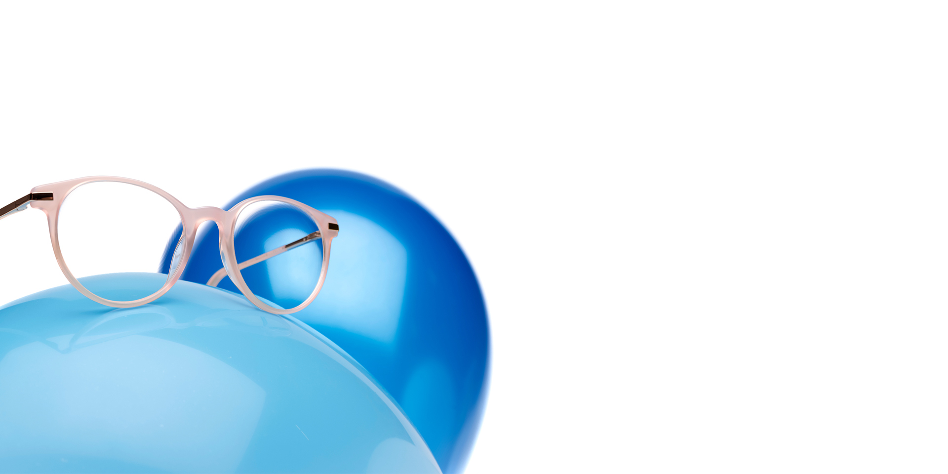 ZEISS MyoCare-glas i en rosabeige båge visas på en ljusblå ballong. I bakgrunden finns ytterligare en, något mörkare blå, ballong.