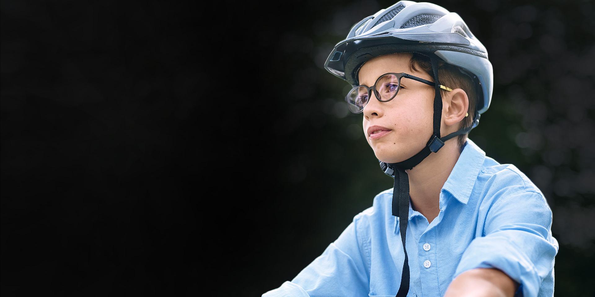 En ung pojke med glasögon och hjälm tycks komma cyklande.