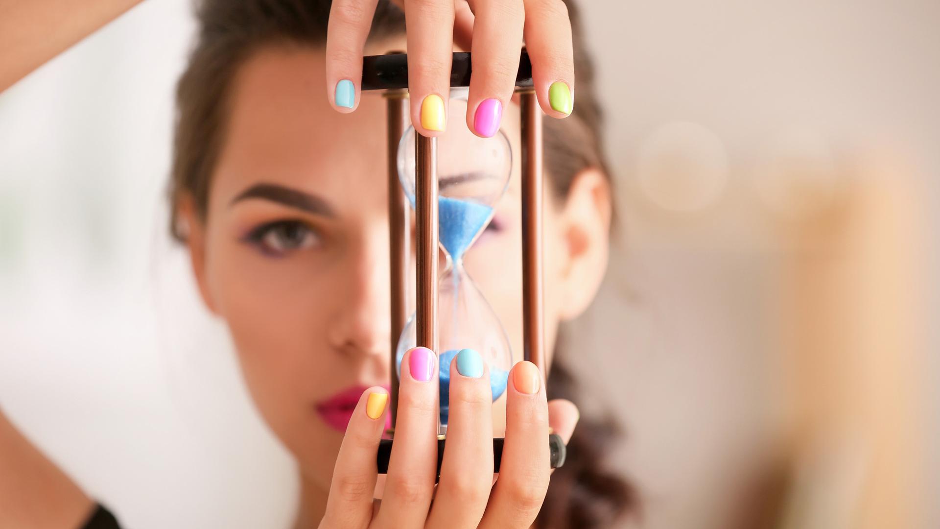 En ung kvinna med målade naglar håller i ett timglas