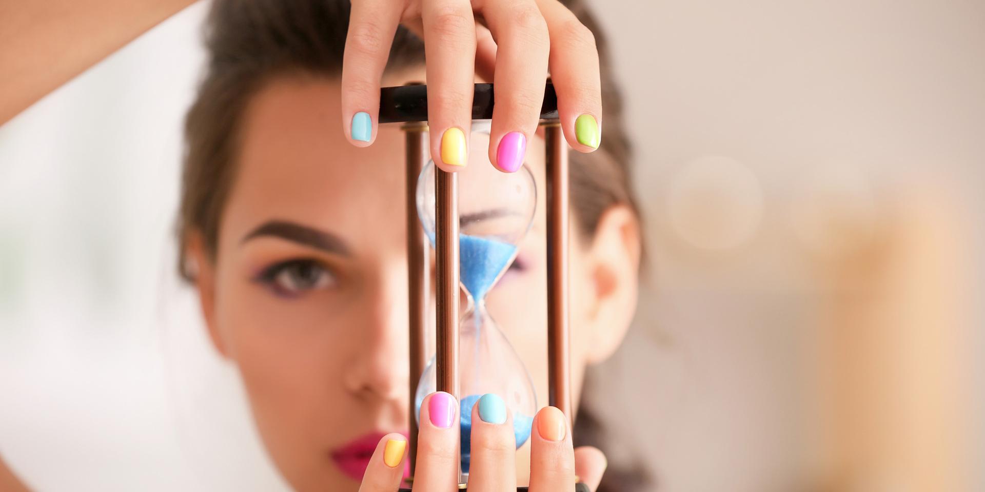 En ung kvinna med målade naglar håller i ett timglas