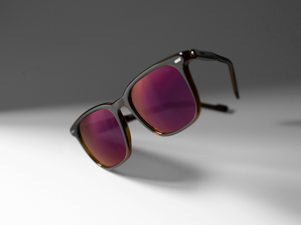 Bild på ett ZEISS-solglasögonglas med styrka i nyansen Burgundy och ZEISS DuraVision Gold ytbehandling.