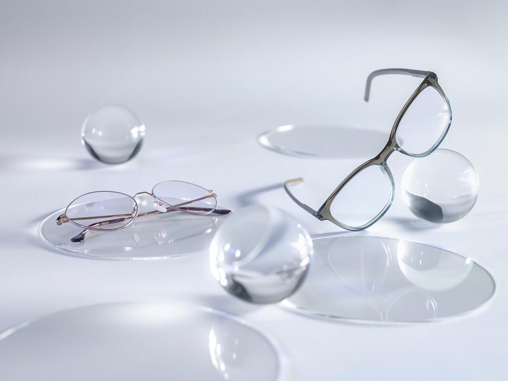 Glasögon med ZEISS-glas försedda med DuraVision® Silver-ytbehandling, utan reflexer jämfört med de omgivande glasrundlarna.