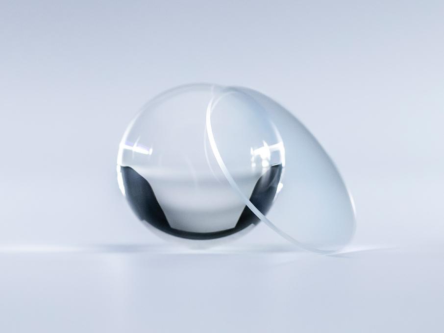 Ett glas med ZEISS Platinum-ytbehandling är kristallklart utan reflexer, jämfört med glasbollen bredvid glaset.