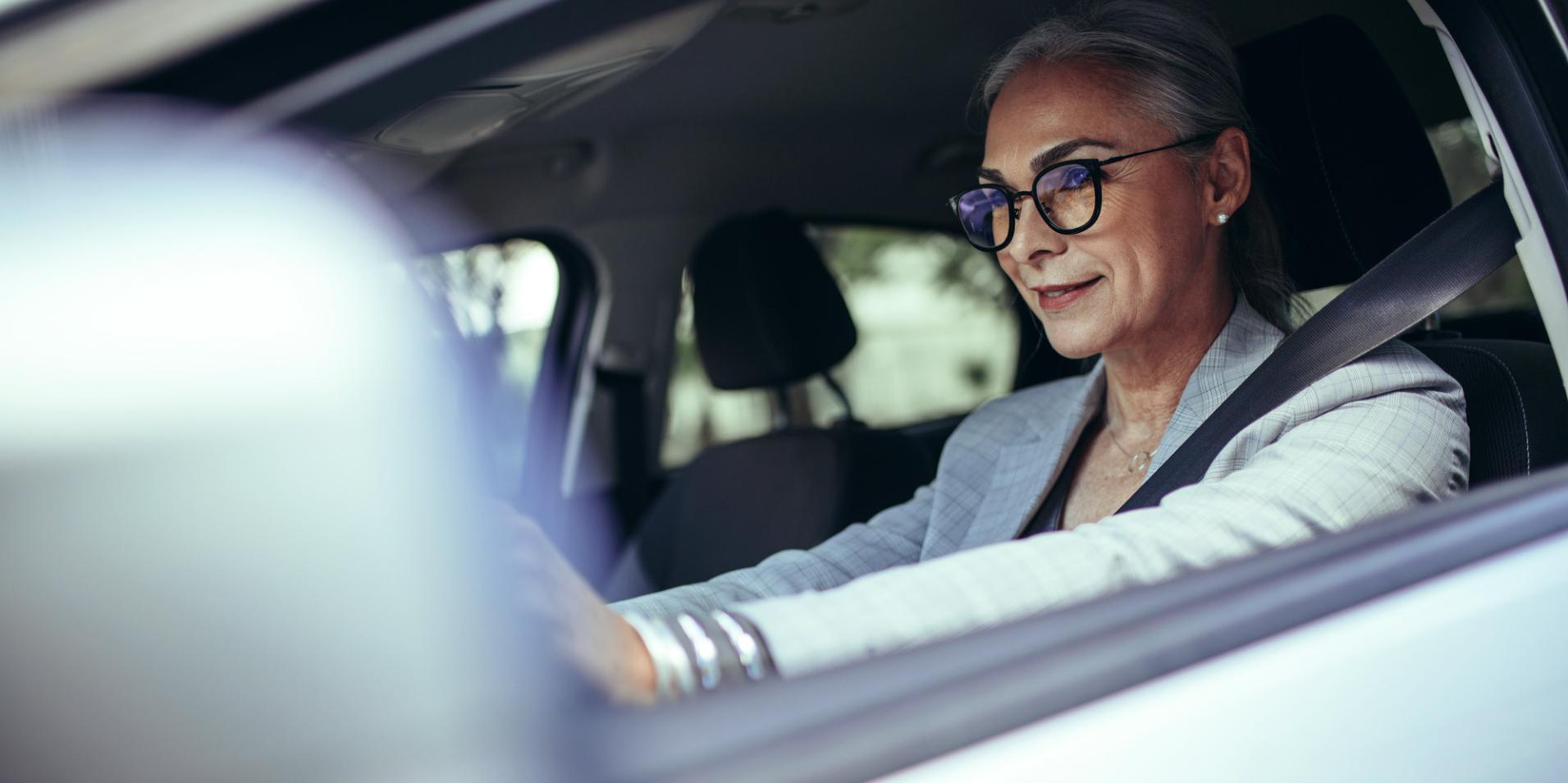 En medelålders kvinna i en bil bär glasögon med ZEISS DriveSafe-glas.