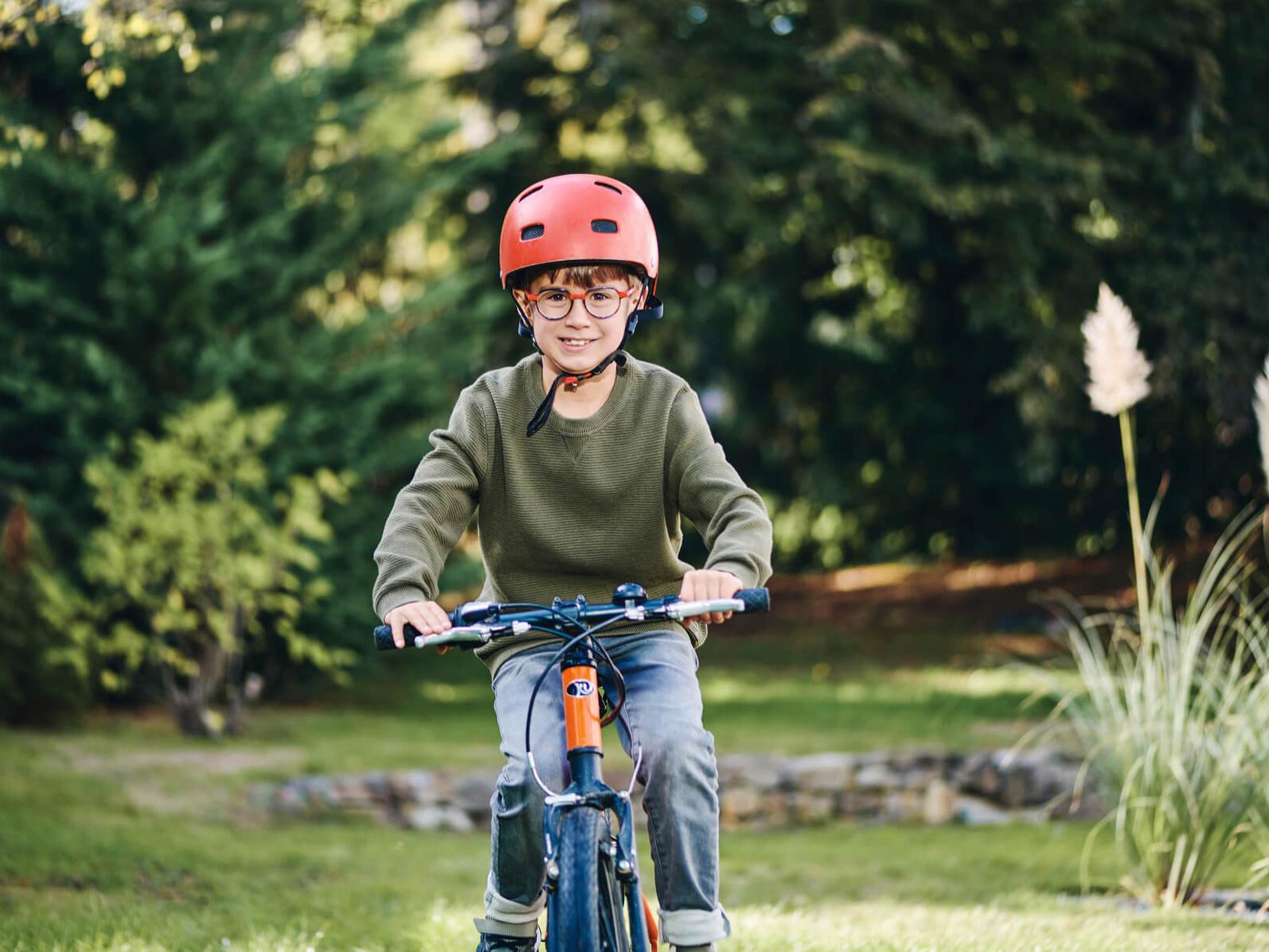 En ung pojke med ZEISS glas för myopihantering cyklar utomhus.