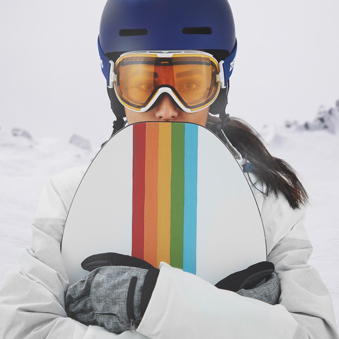 En kvinna bär en blå hjälm och ett par skidglasögon från ZEISS med transparent frontlins.