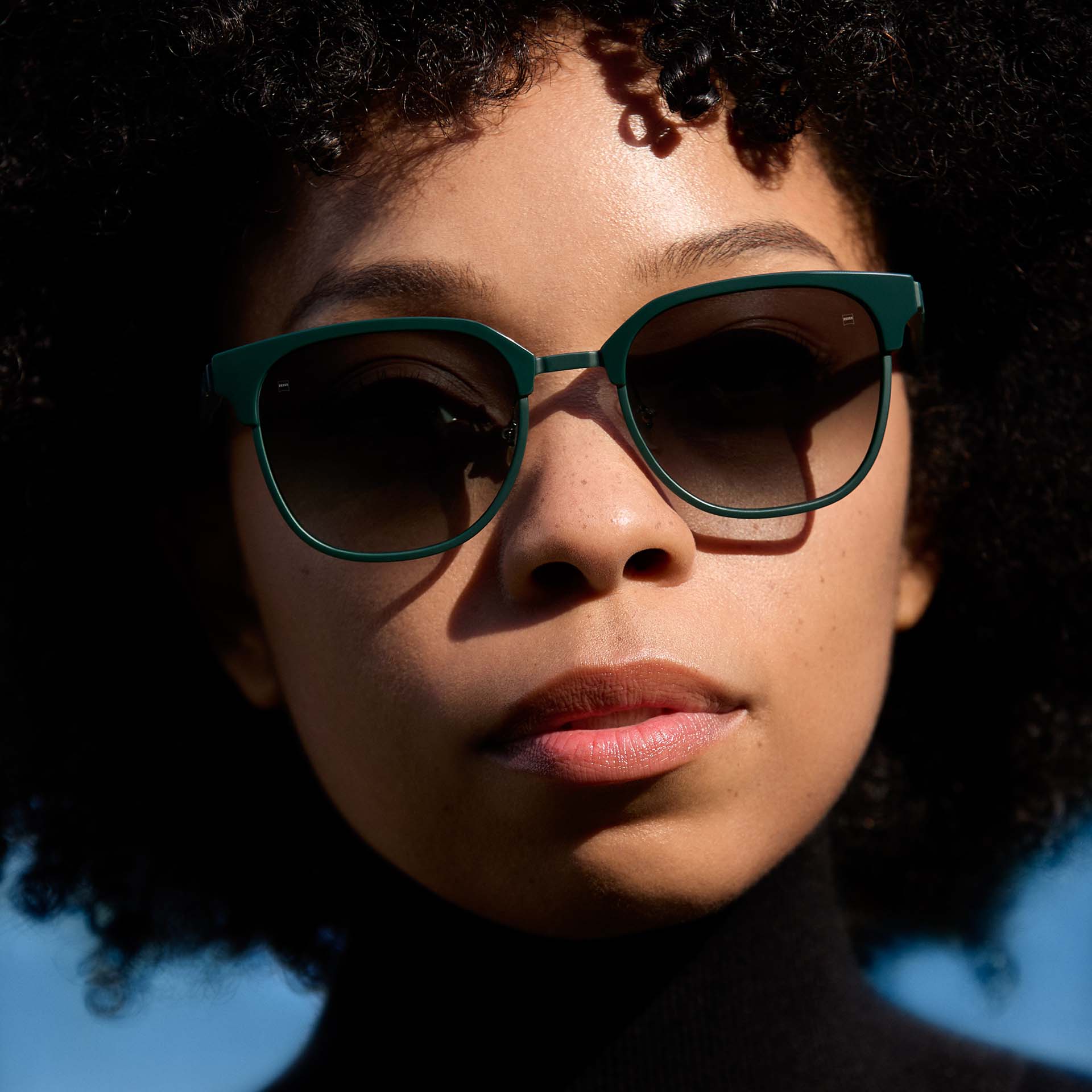 En kvinna bär en grön båge med glas i gradalfärg. 