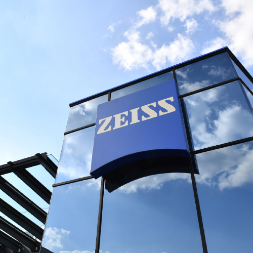 En bild på en modern glasbyggnad med en stor ZEISS-logotyp. 