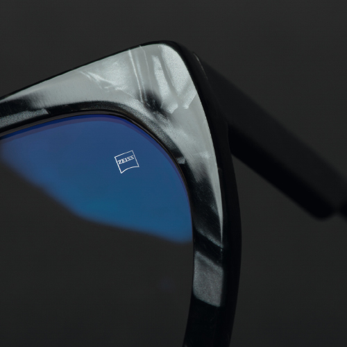 En närbild på ett glasögonglas i en svart båge med ZEISS synligt ingraverat. 