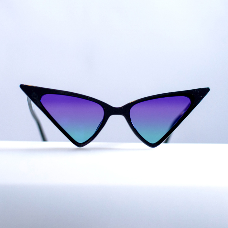 Fantastiska cat eye-solglasögon mot en vit yta, med blålila gradalfärg